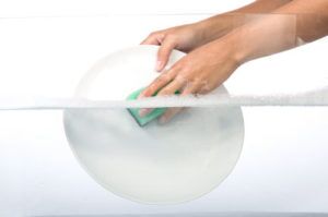 Person washing plate with sponge