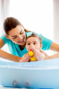 mom giving baby a bath - Plumbing, sewer, & drain services in Peoria IL