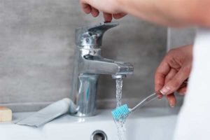 Woman Washing Her Tooth Brush — Peoria, IL — Arnold & Sons Plumbing Sewer & Drain Services