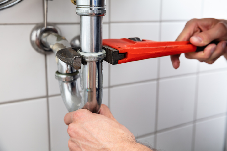 Close-up Of A Plumber's Hand Repairing Sink With Adjustable Wrench